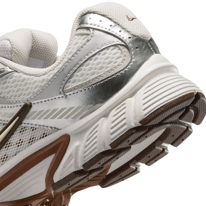 Close-up side of white Nike sneakers showing tread ridges and light-brown sole accents.