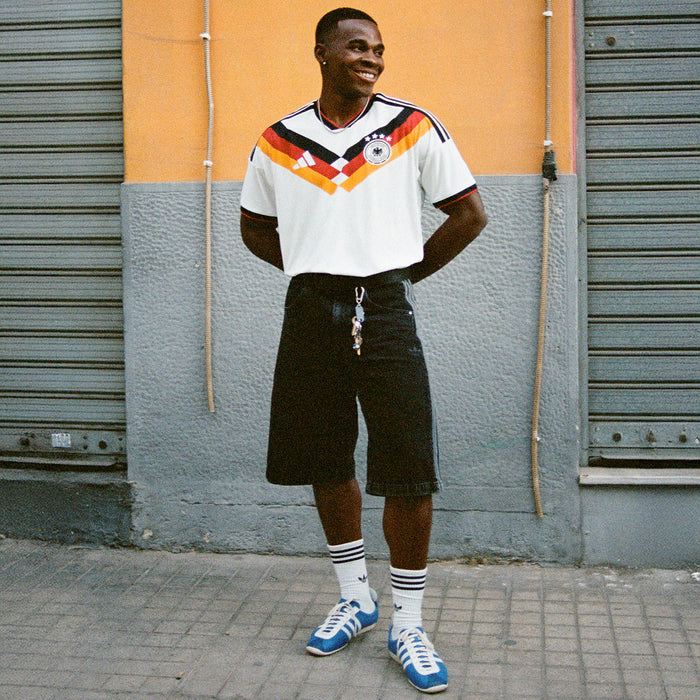 Men's white Germany home soccer jersey with multicolor V graphic and short sleeves