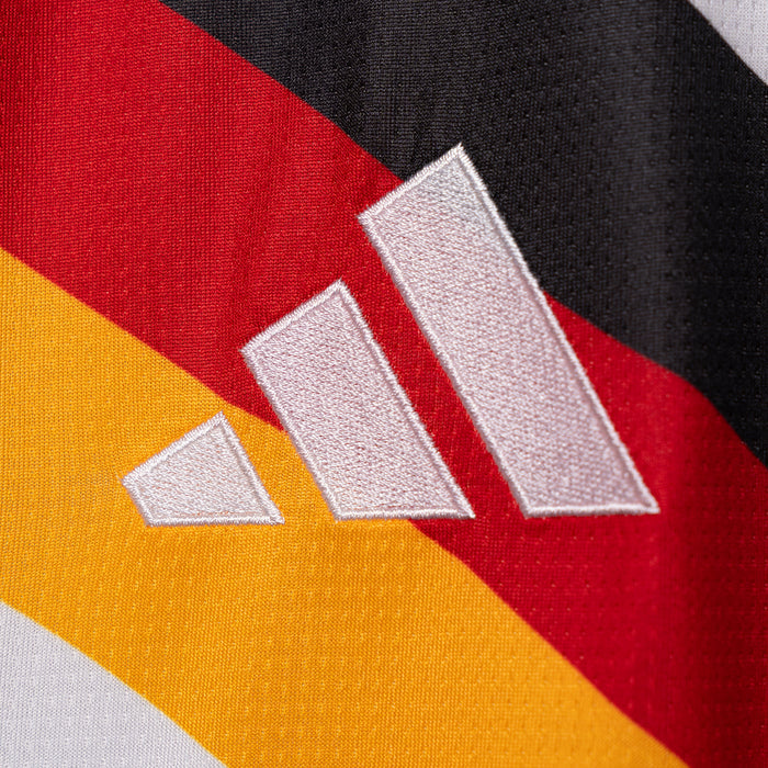 Adidas three-stripe logo on white jersey with red and gold diagonal accents