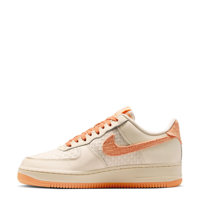 Women’s Air Force 1 low-top sneakers, cream upper with orange swoosh and lace-up detail.