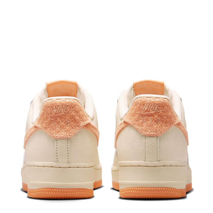 Women’s Air Force 1 sneakers with orange heel tab and cream back panels, gum sole.
