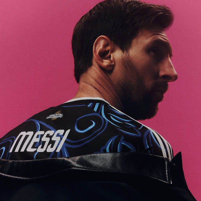 Black jersey shoulder close-up with blue swirls and white MESSI text