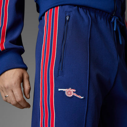 Blue track pants with zip pocket and embroidered crest on left thigh