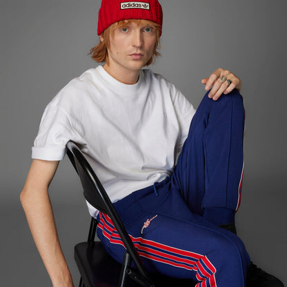 Folded men’s blue track pants with red and white stripe detail and crest logo