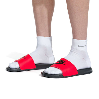Red and black slide sandals with Nike logo on model wearing white socks