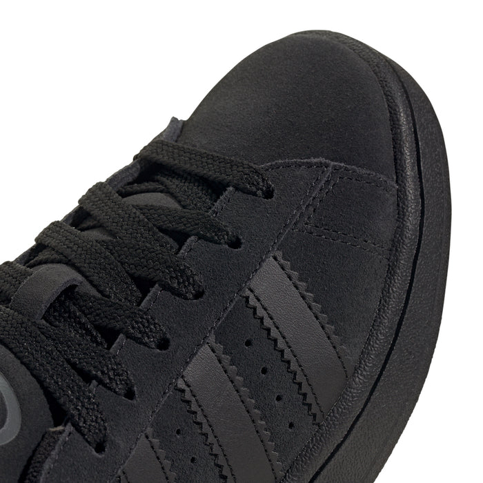Close-up of black suede sneaker upper with lace eyelets and three stripes