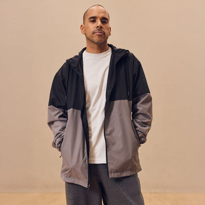 Mens black hooded windbreaker with gray colorblock panels, worn open over a shirt