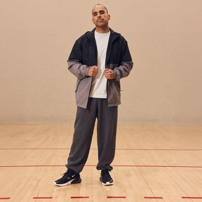 Mens windbreaker with black hood and gray panels, worn open with hands in front