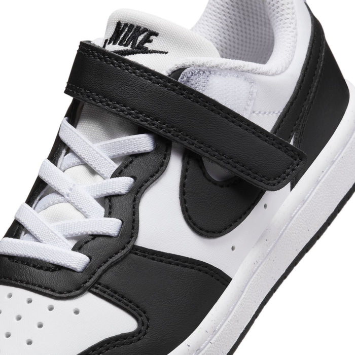 Kids sneaker close-up: white laces, black Nike swoosh, and hook-and-loop strap detail