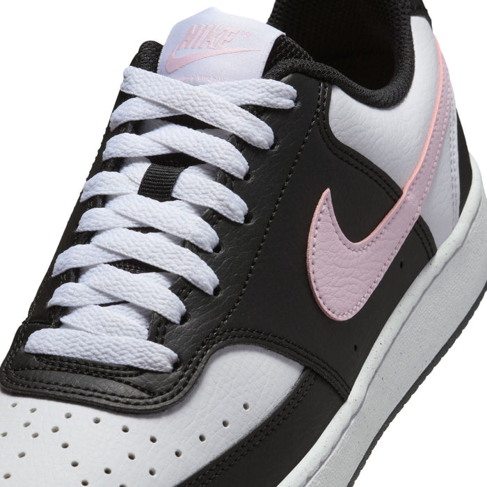 Close-up of low-top sneaker laces and pink swoosh on black and white leather upper