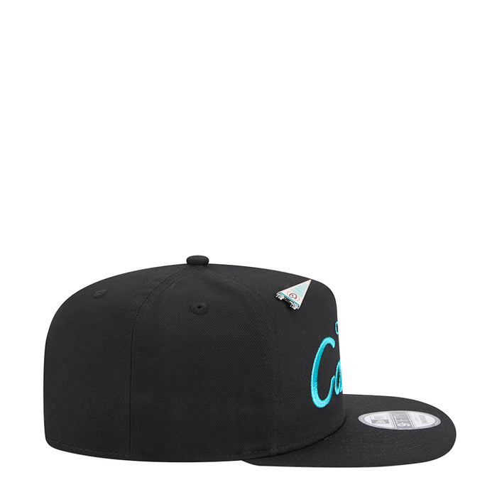 Black A-frame baseball cap, side view with teal lettering and small team logo patch