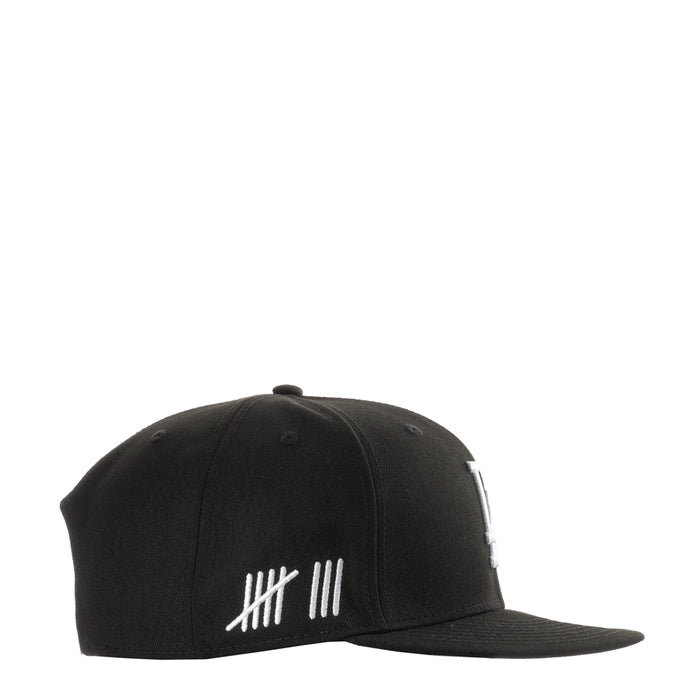 Black baseball cap with white striped graphic on front panel