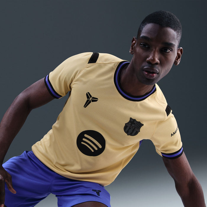 Men's soccer jersey in pale yellow with dark blue trim, FCB crest and circular emblem.