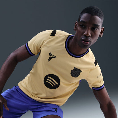 Men's soccer jersey in pale yellow with dark blue trim, FCB crest and circular emblem.