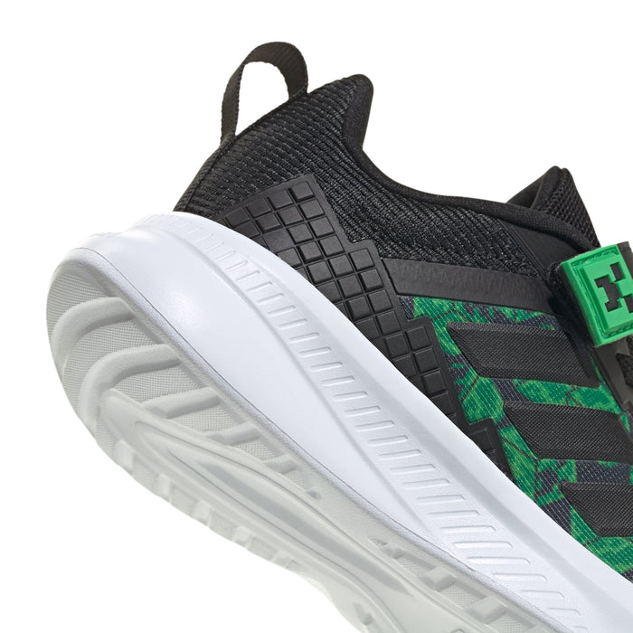 Kids' black sneaker with green logo patch and white treaded outsole