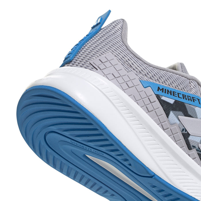 Youth shoe heel close-up: textured gray upper, white midsole, blue tread and pull tab.