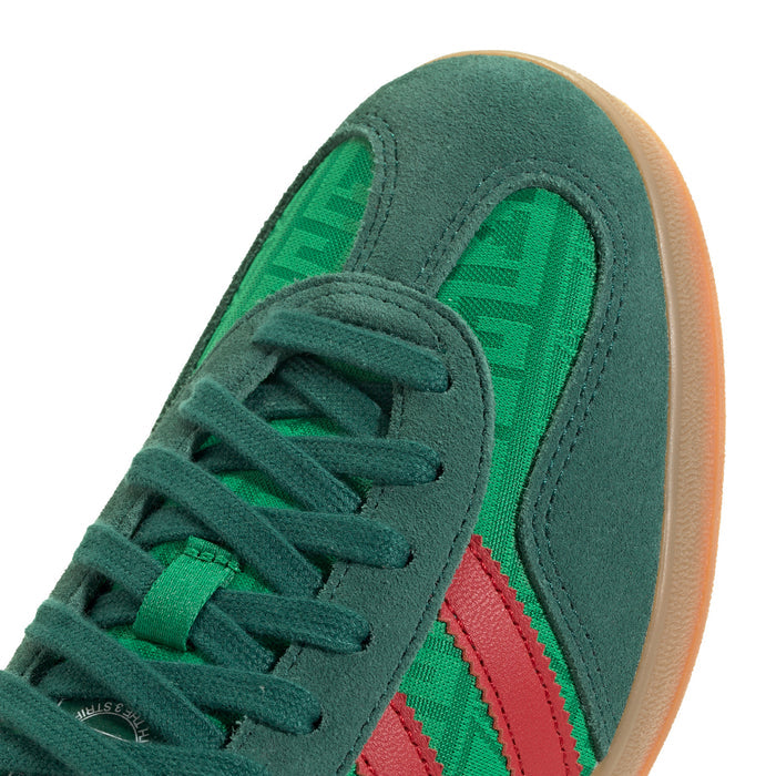 Green suede toe and lace area with textured pattern and red stripe accent.