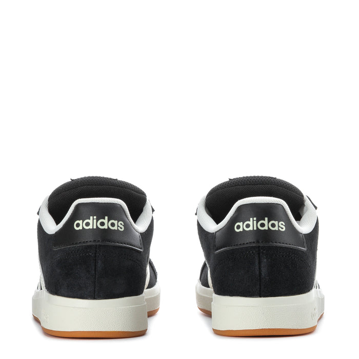 Youth Adidas sneakers in black with white stripes and gum outsole, heel view.