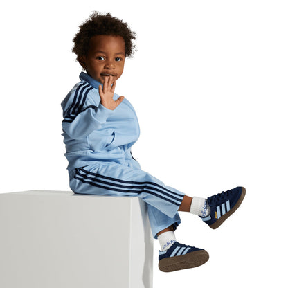 Toddler navy sneakers with light blue stripes, worn by a child in a light blue outfit