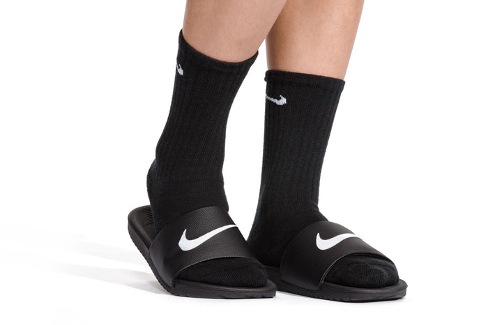 Youth slide sandals worn with black socks; white swoosh on straps