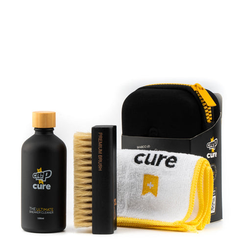 Sneaker cleaning kit with black bottle, bamboo brush, and yellow cloth pouch