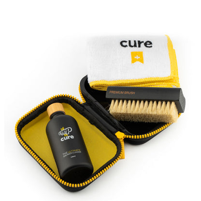 Sneaker cleaning kit with open cases, bamboo brush, black bottle, and yellow cloth