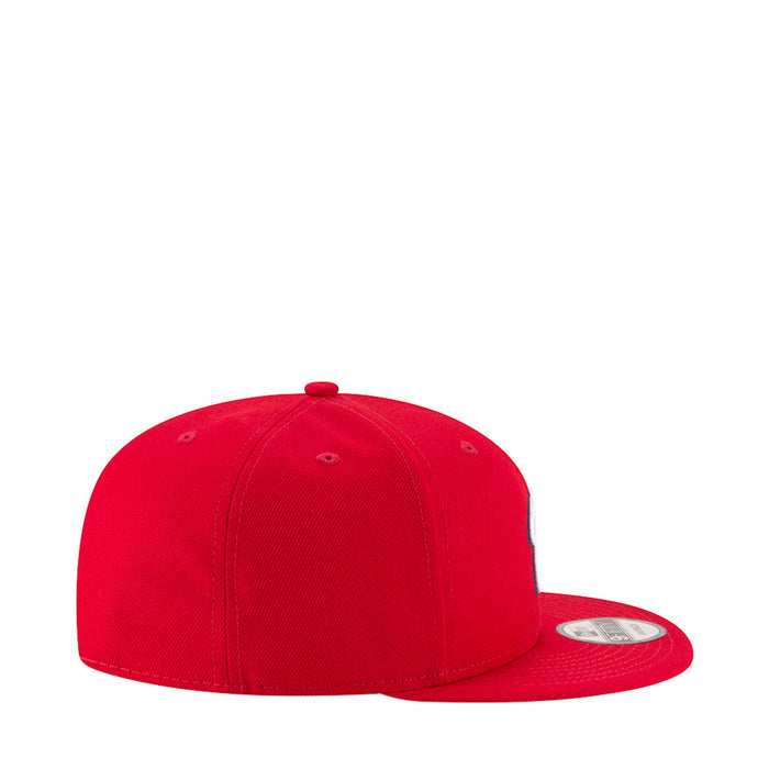Red baseball cap with stitched panels and top button, side view