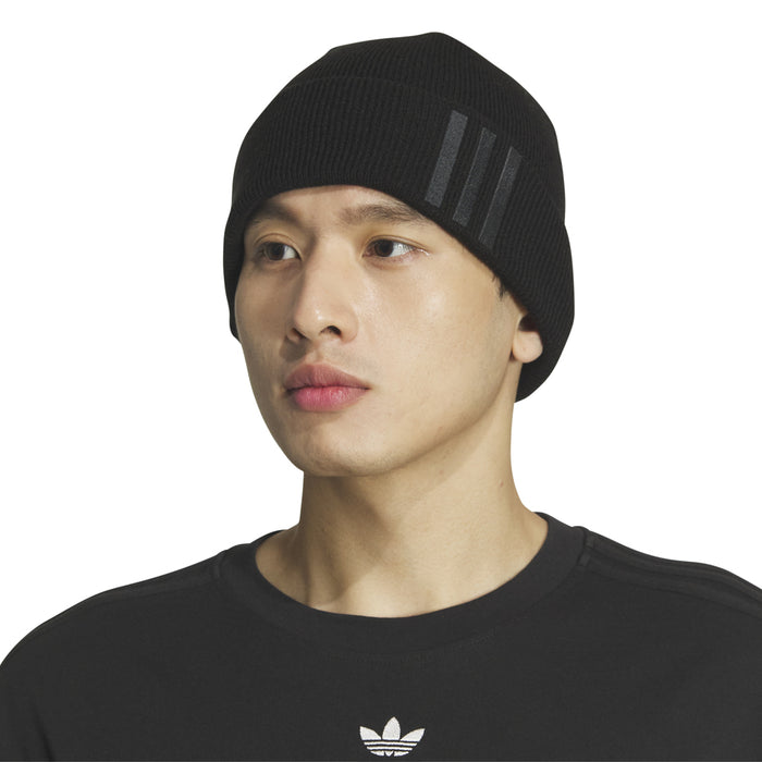 Black knit beanie worn by model, fold-over cuff with three-bar logo