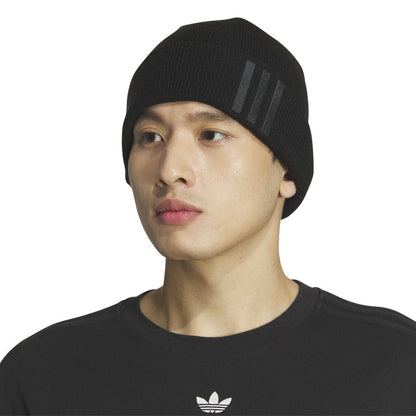 Black knit beanie worn by model, fold-over cuff with three-bar logo