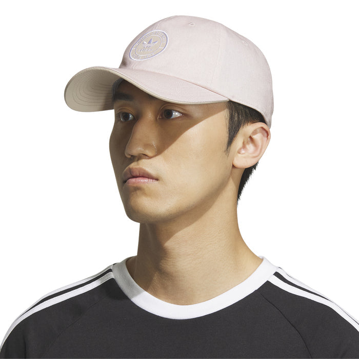 Light pink strapback cap with small Adidas logo patch; worn by model
