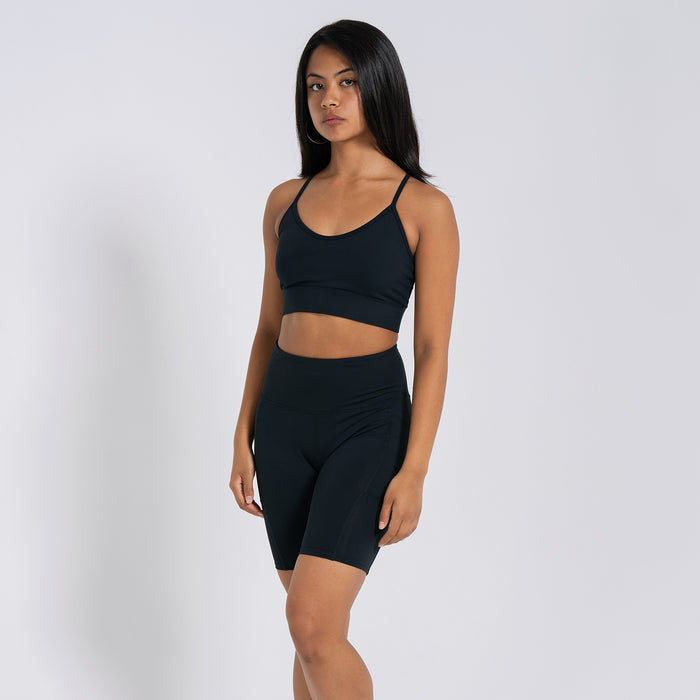 Women’s black high-waist bike shorts worn with matching sports bra, fitted mid-thigh