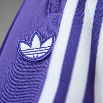 Purple track pants detail: adidas trefoil logo with white triple stripes