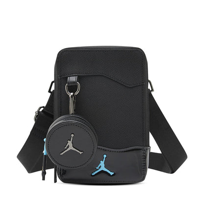 Black crossbody bag with zip top, front flap, and blue Jumpman logo patch