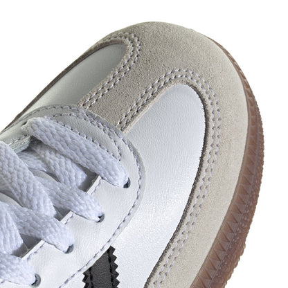 Kids white low-top sneaker close-up with laces, stitched overlays, and gum-brown sole