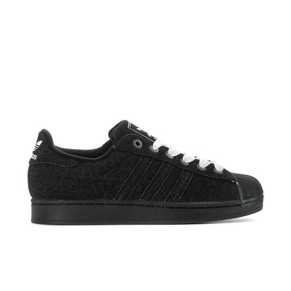 Black low-top canvas sneakers with white laces and side stripes, rubber sole