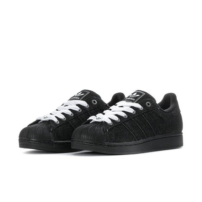 Pair of black low-top sneakers with white lace-up details and black rubber sole