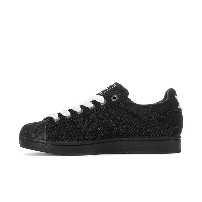 Black low-top adidas sneakers with white laces, side stripes, and black outsole