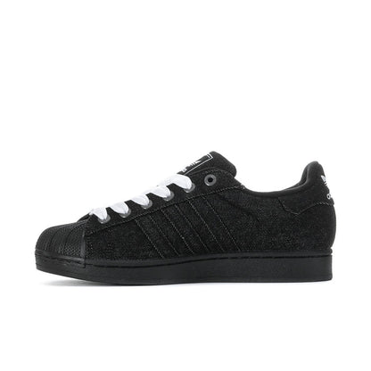 Black low-top adidas sneakers with white laces, side stripes, and black outsole