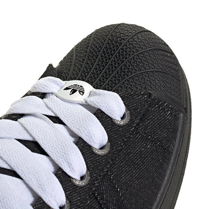 Close-up of black sneaker side with white laces and textured fabric upper