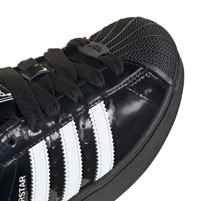Youth sneaker upper close-up: black patent with white stripes and lace details