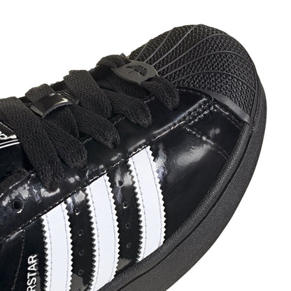 Youth sneaker upper close-up: black patent with white stripes and lace details