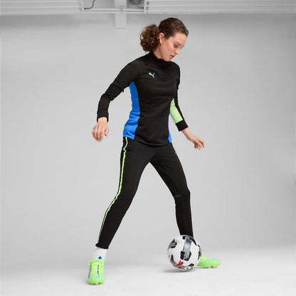 Men's lime green FG/AG soccer cleats with blue laces worn with black track pants.