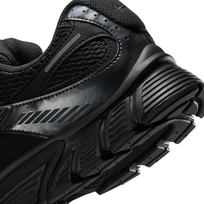 Men's black sneaker heel close-up with ridged traction sole and metallic side stripe