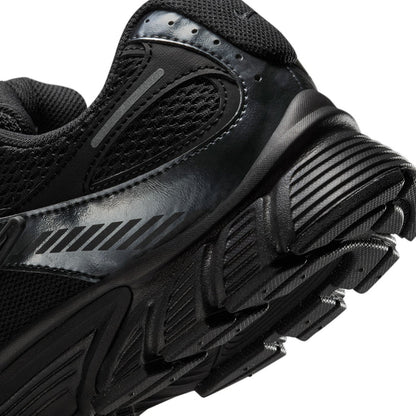 Men's black sneaker heel close-up with ridged traction sole and metallic side stripe