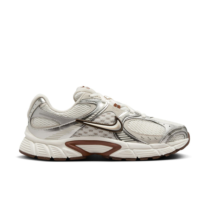 White and light-brown Nike running sneakers, side profile with swoosh and cushioned sole.