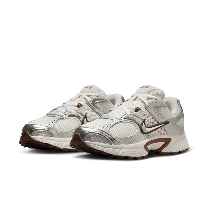White Nike running sneakers with light-brown accents, front three-quarter view.