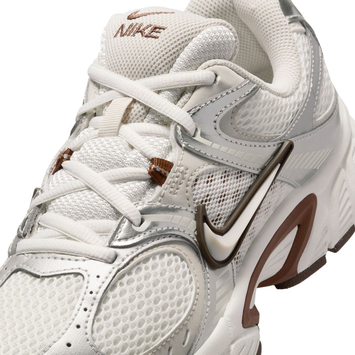 Close-up of white Nike sneakers with mesh upper, laces, swoosh, and brown logo tag.