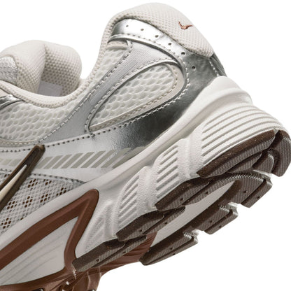 Close-up side of white Nike sneakers showing tread ridges and light-brown sole accents.