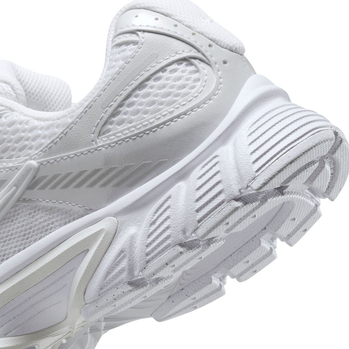 Close-up of white sneaker side with mesh paneling, lace eyelets, and outsole tread