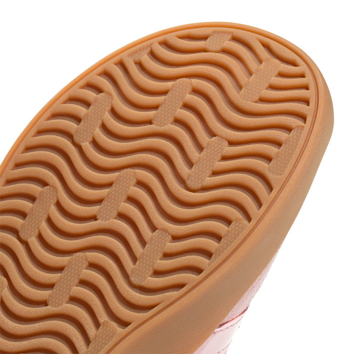 Youth sneaker outsole close-up with wavy tread pattern in tan